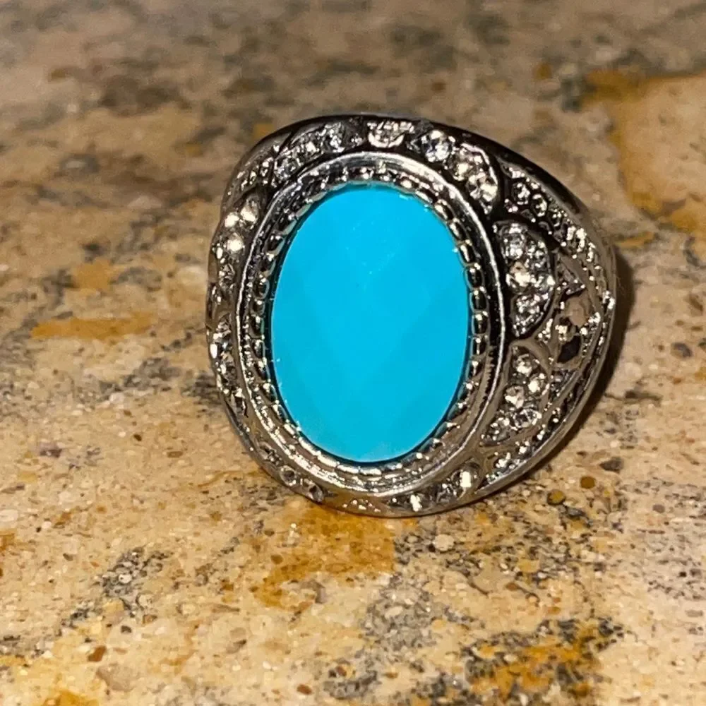 Costume jewelry silver tone ring with turquoise color acrylic center stone.